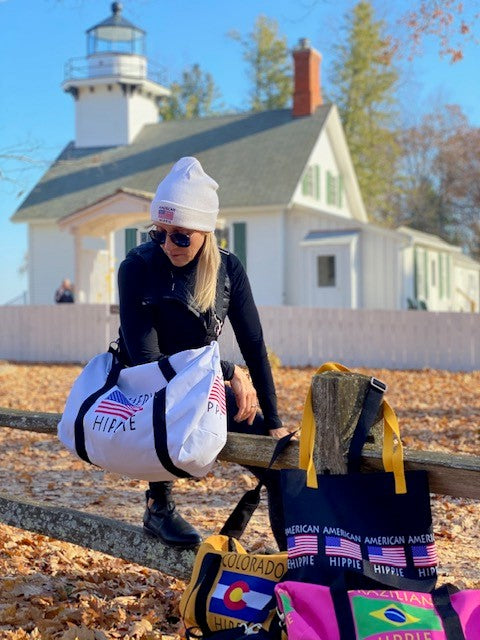 Stately Wear flag hippie duffels, stately wear flag hippie totes & stately wear flag hippie beanies on full display at Old Mission Peninsula lighthouse, plus a stately wear colorado flag hippie duffel bag and stately wear brazilian flag hippie duffel bag
